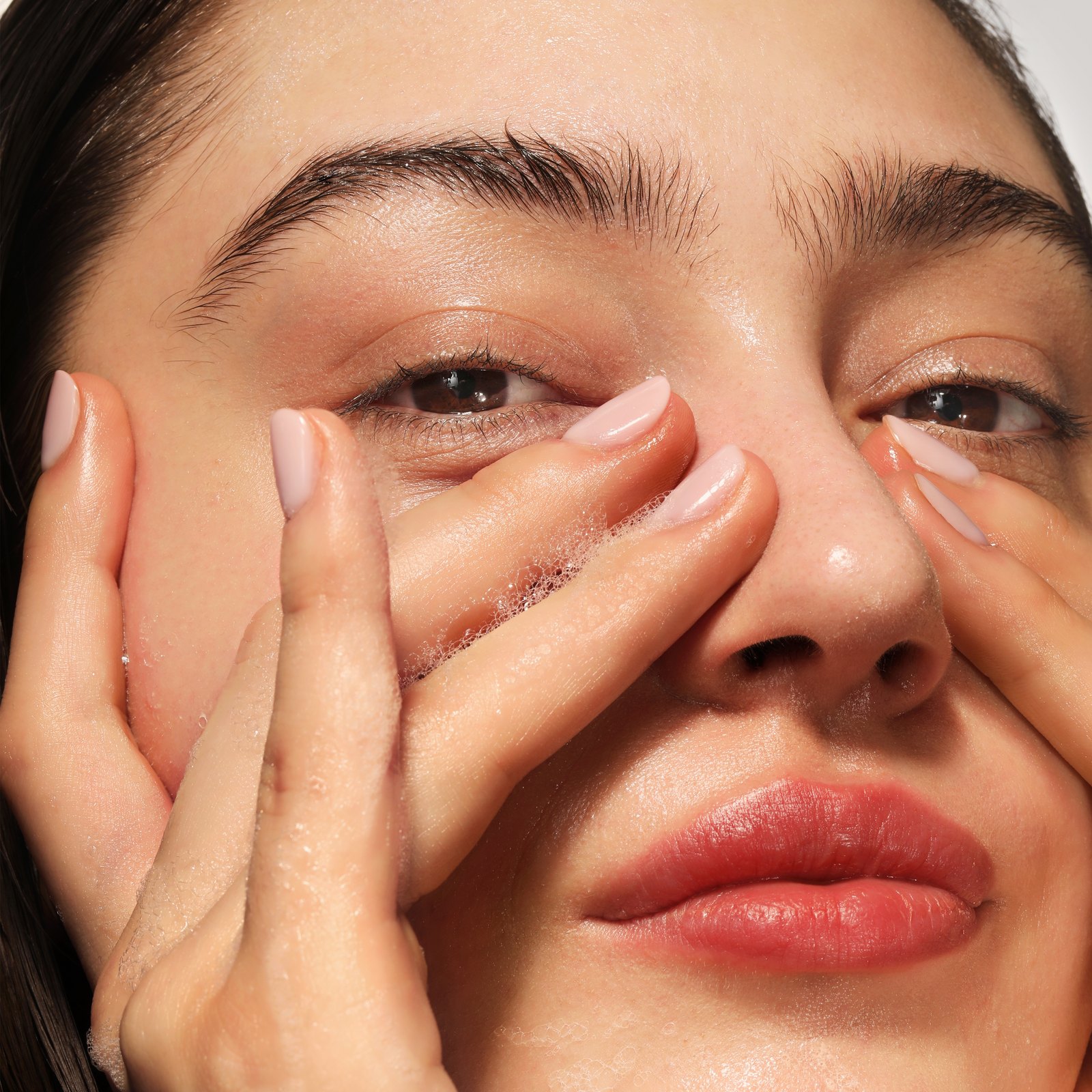 A woman washing her face with a soft cleansing foam