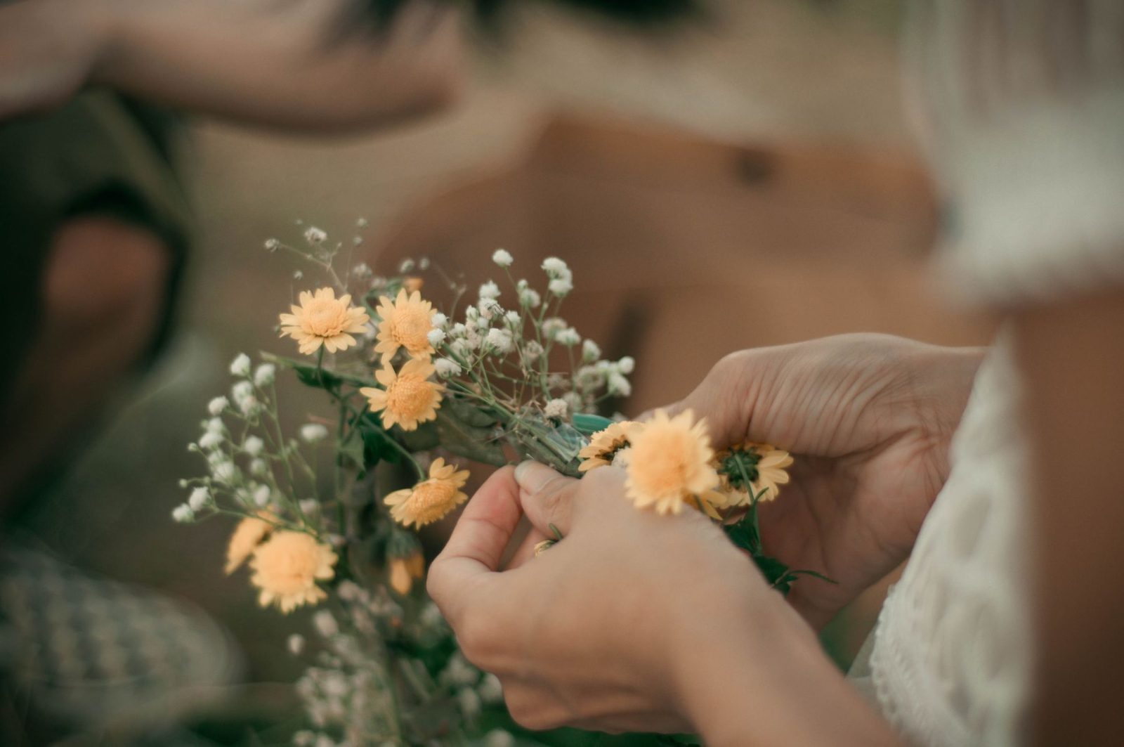 Hands gently putting together a small bouquet of flowers
