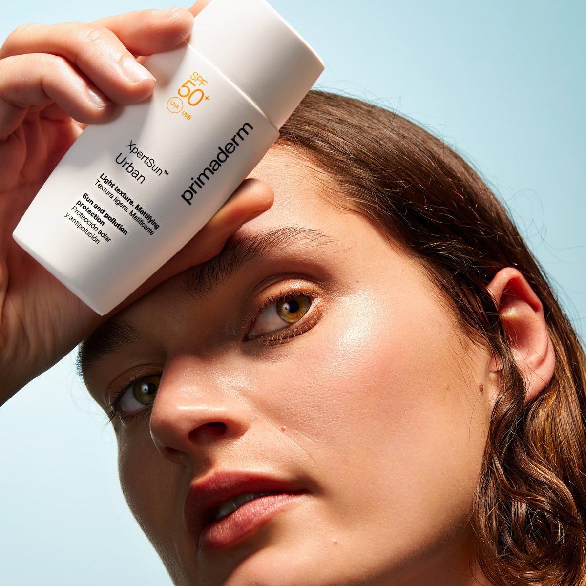 Woman holding XpertSun Urban sunscreen against her forehead