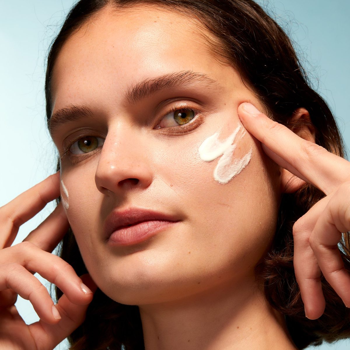 Woman applying XpertSun Urban Advanced sunscreen to her cheek