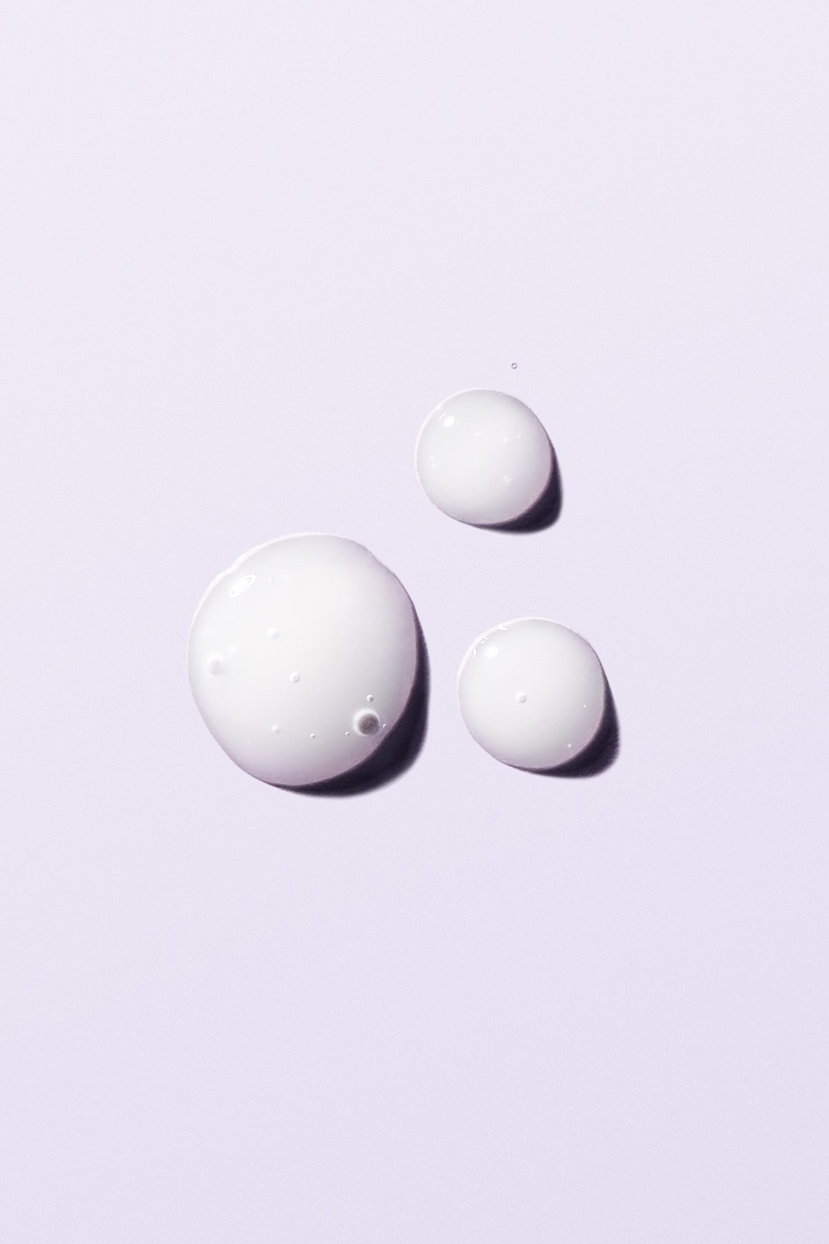 Three drops of Booster SOS on a lilac surface